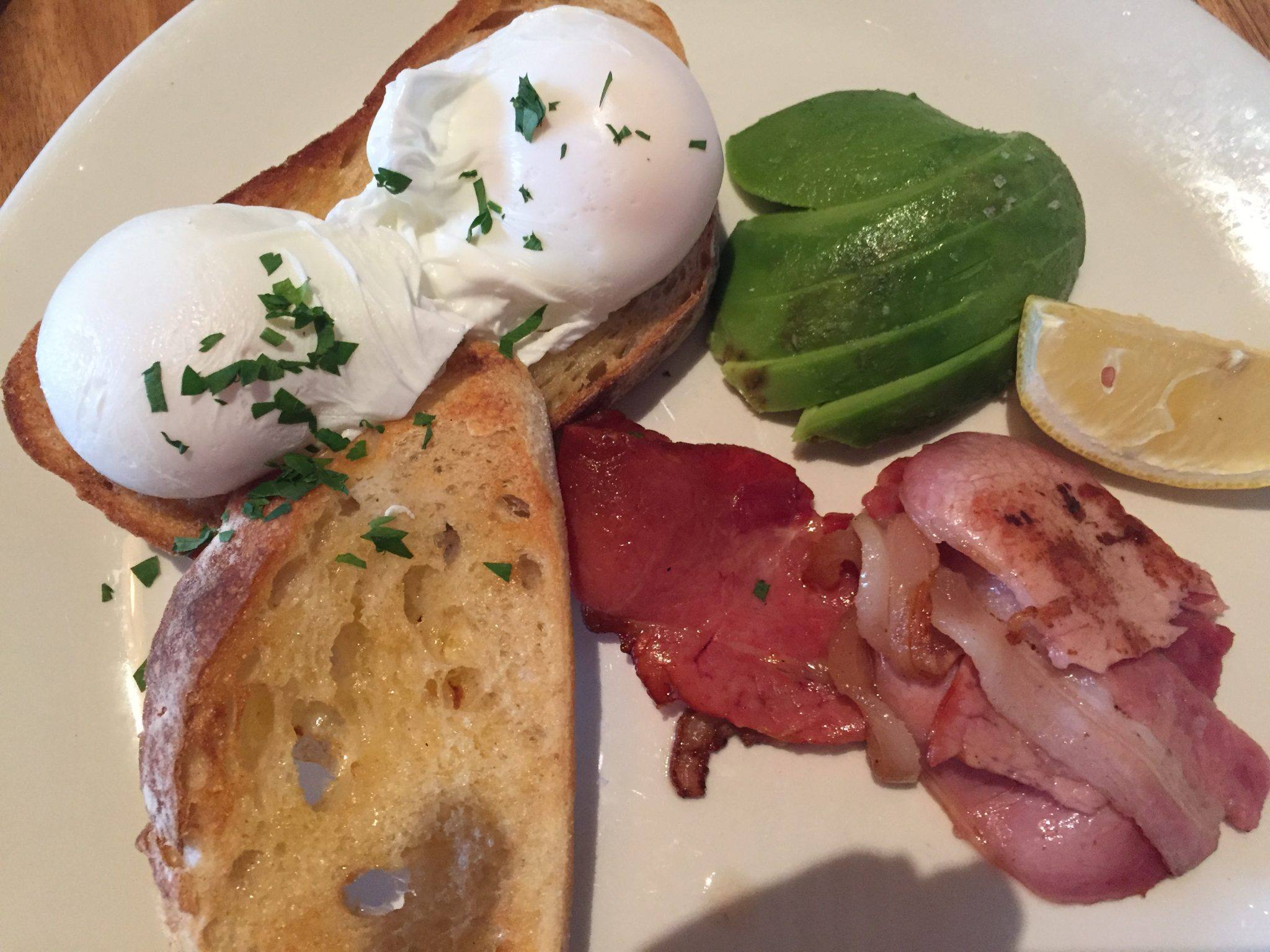 Daylesford Spa Ultimate Weekend Guide 2 toast with poached eggs, bacon and avocado on a white plate at cafe koukla daylesford