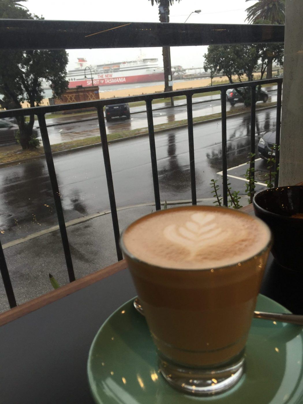 flat white with a rainy beach backdrop at cafe lafayette in port melbourne