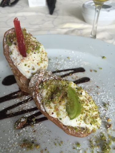 2 pieces of cannoli with chocolate sauce drizle and kiwi fruit and covering 