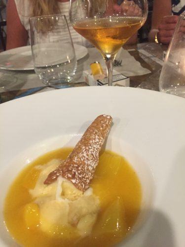 a cone in a plate with lemon sauce and ice cream and glass of wine in the background hotel signum sicily