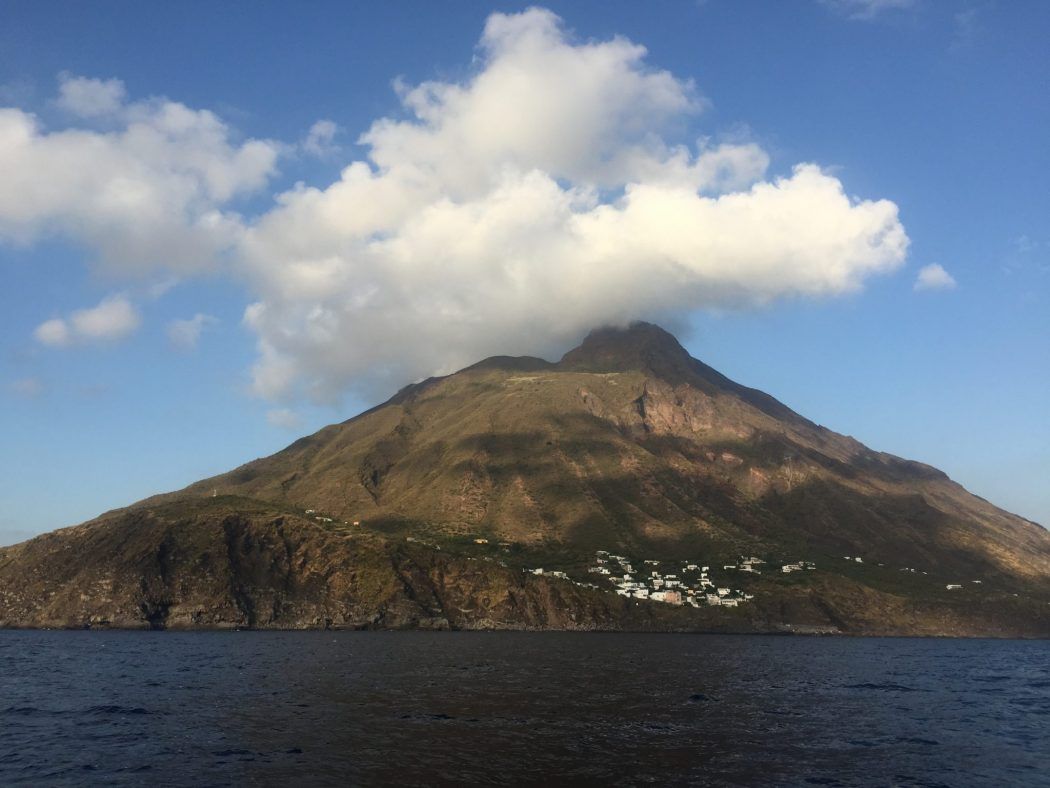 uma ilha aeolian visto a partir de um barco com as nuvens no topo