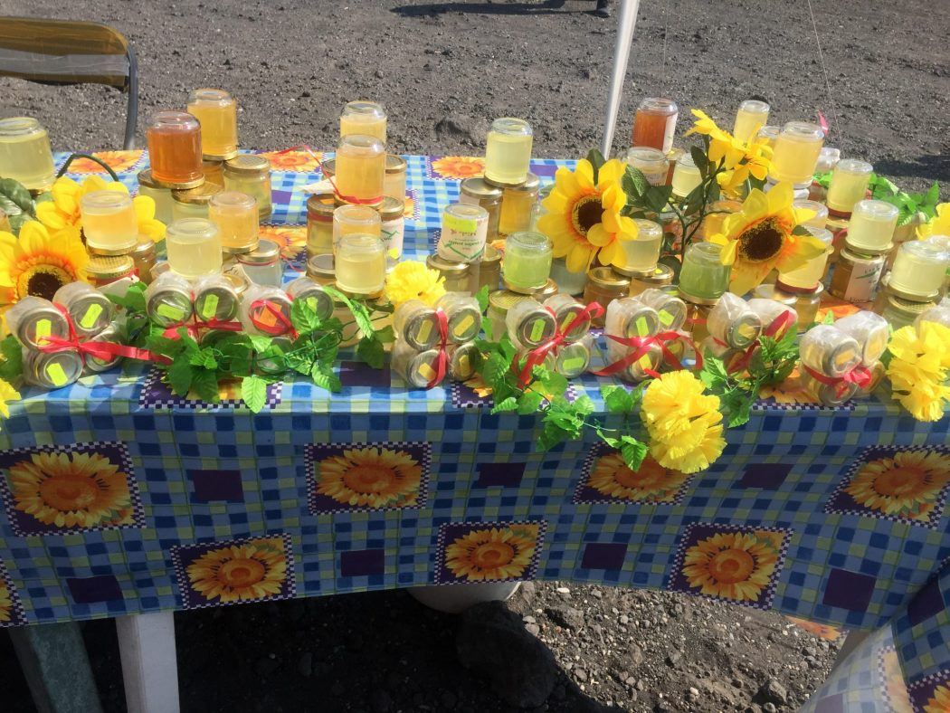 mesa colorida con miel a la venta y girasoles