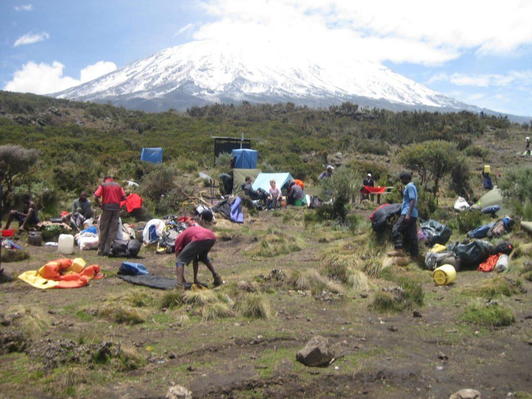 people setting up a camp with Mount Kilimanjaro in the background solo travel groups