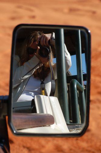 woman taking a photo into a car rearview mirror how to travel solo