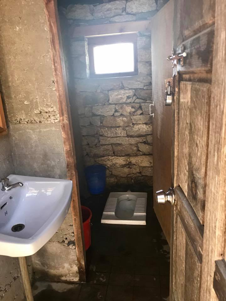 squat toilet in a bathroom with sink on the everest base camp trek