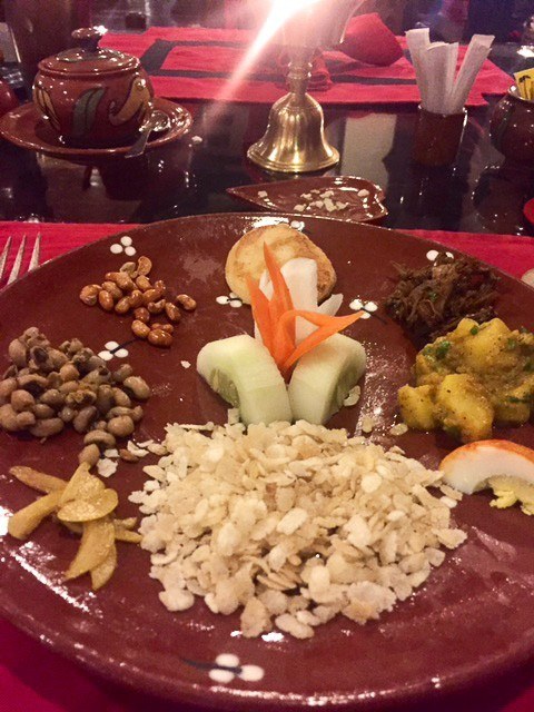 course of nuts and delicacies on a red plate at krishnarpan restaurant