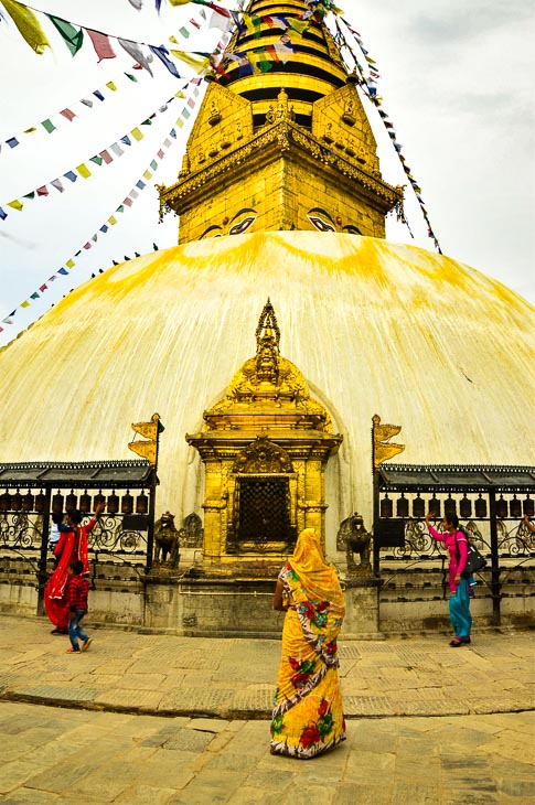 woman in a yellow sari from behind in front of the top of swayambhunath stupa kathmandu nepal