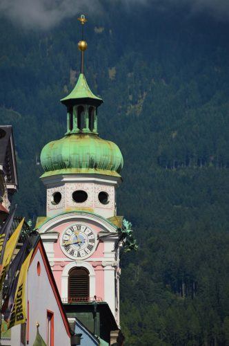 colourful steeple with old fashioned clock and mountains behind innsbruck colourful steeple with old fashioned clock and mountains behind innsbruck