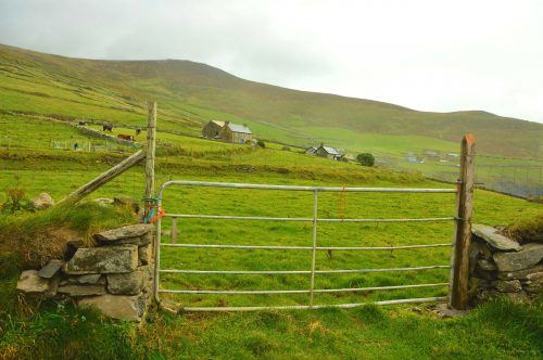 gate with grassy hill and houses in background dingle peninsula ireland gate with grassy hill and houses in background dingle peninsula ireland