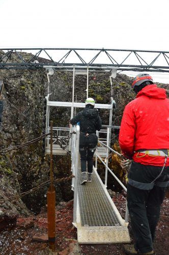 person crossing a steel path to a steel lift on the inside the volcano iceland tour