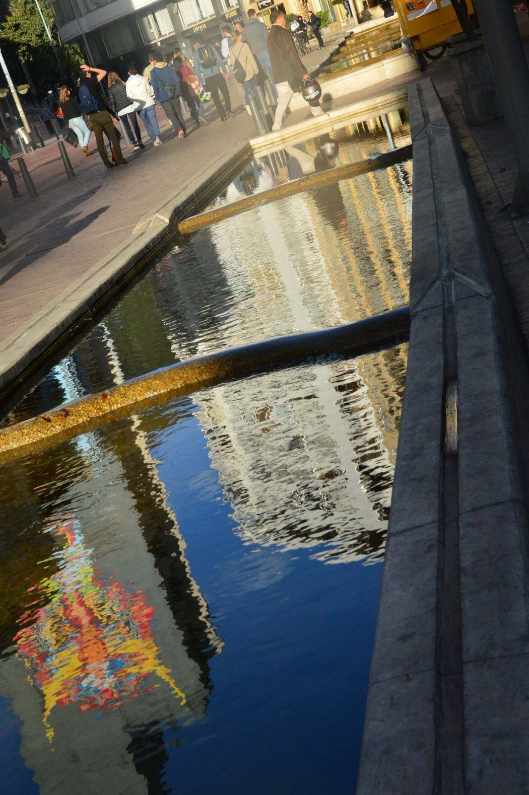 White building and street art reflected in water bogota