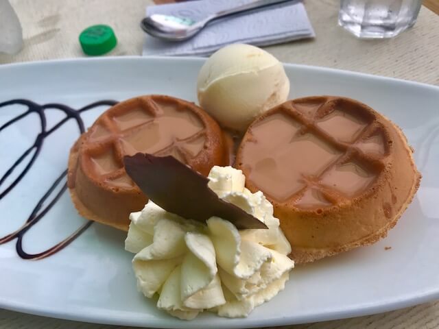 waffles with caramel sauce, cream and vanilla ice cream on a white plate