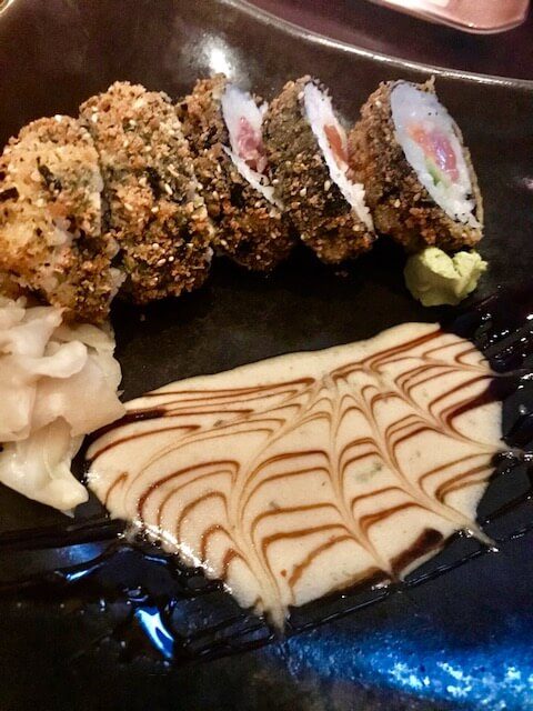 sushi with a white sauce on a dark plate