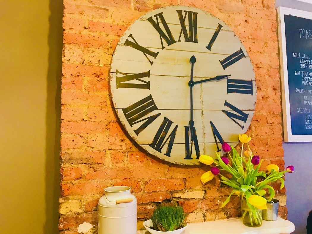 clock against brick wall with flowers at belle amie earlsfield