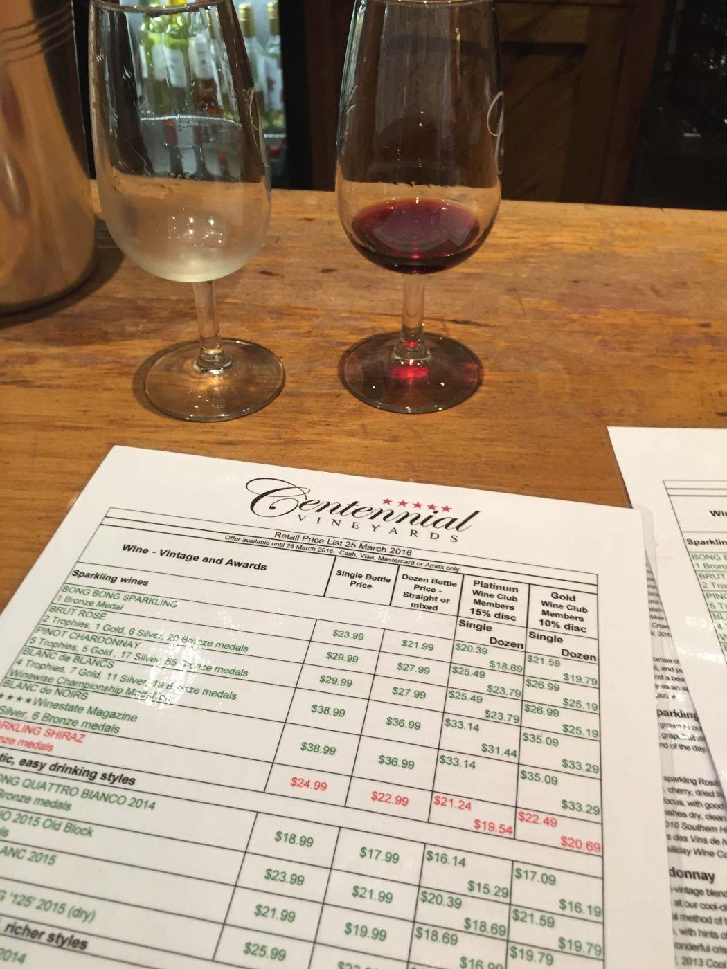 two glasses of wine and a price list at Centennial Vineyards