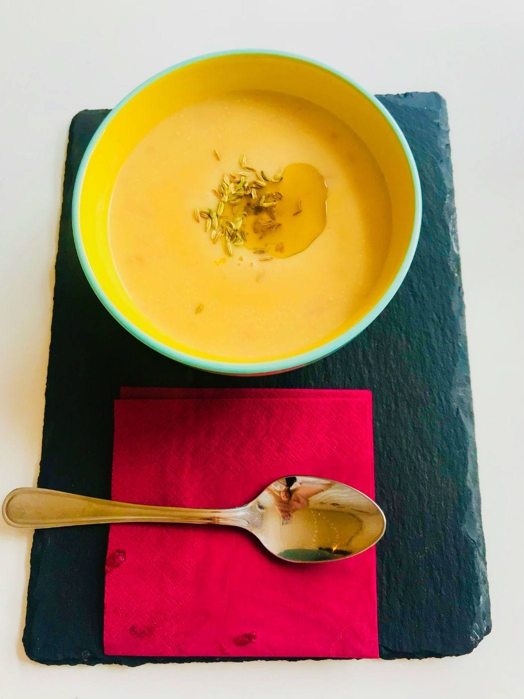 bowl of chicken soup on a black slate with a red napkin and spoon
