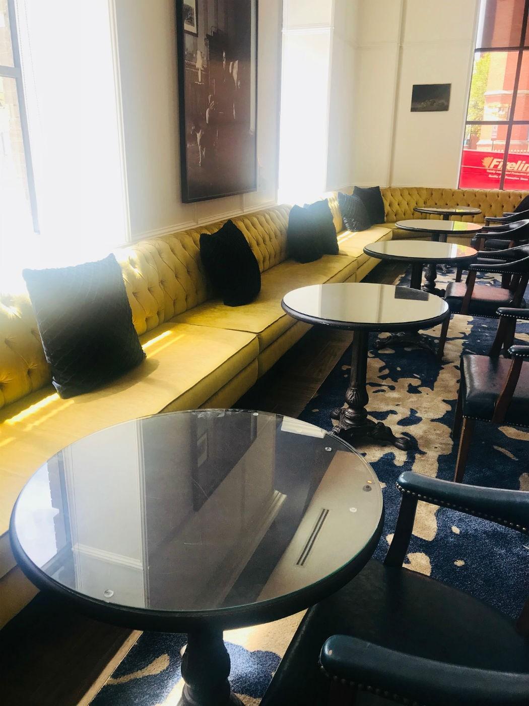 mustard yellow long couches with dark blue cushions and glass tables