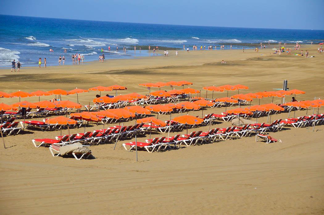 orange umbrellas and red sun loungers on Maspalomas beach