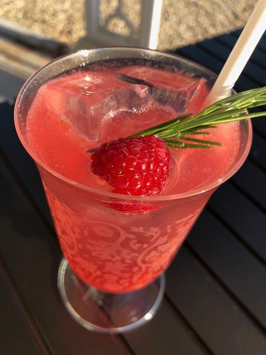 pink cocktail with strawberry and rosemary in a glass