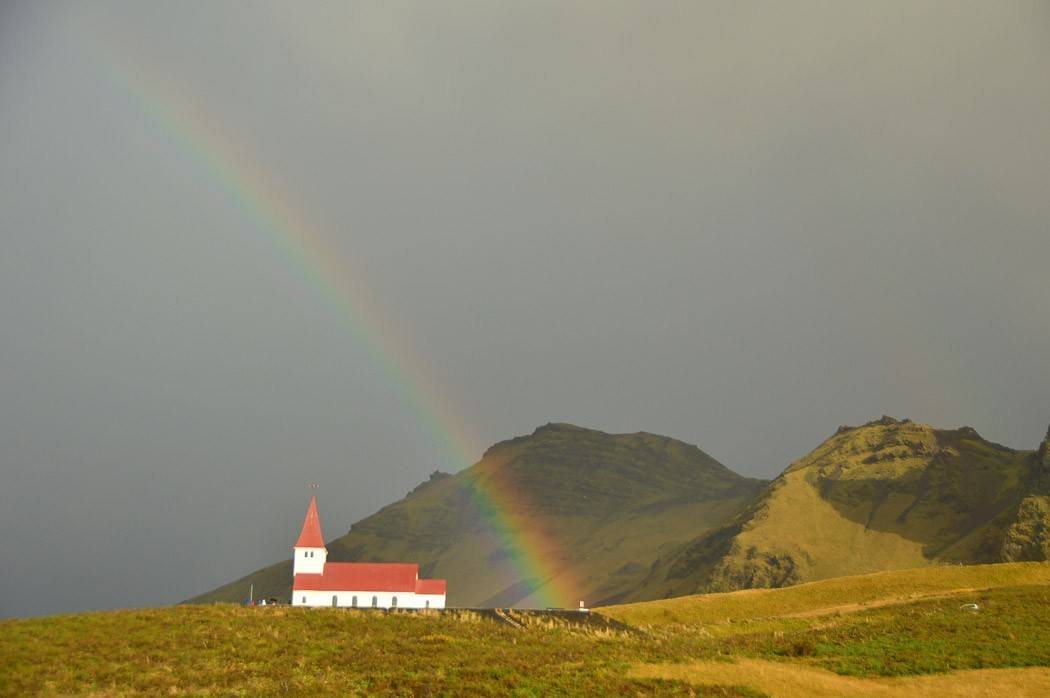 rainbow over a small church in Vik Iceland