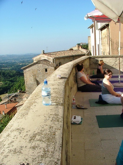 several women sitting on yoga mats on a terrace