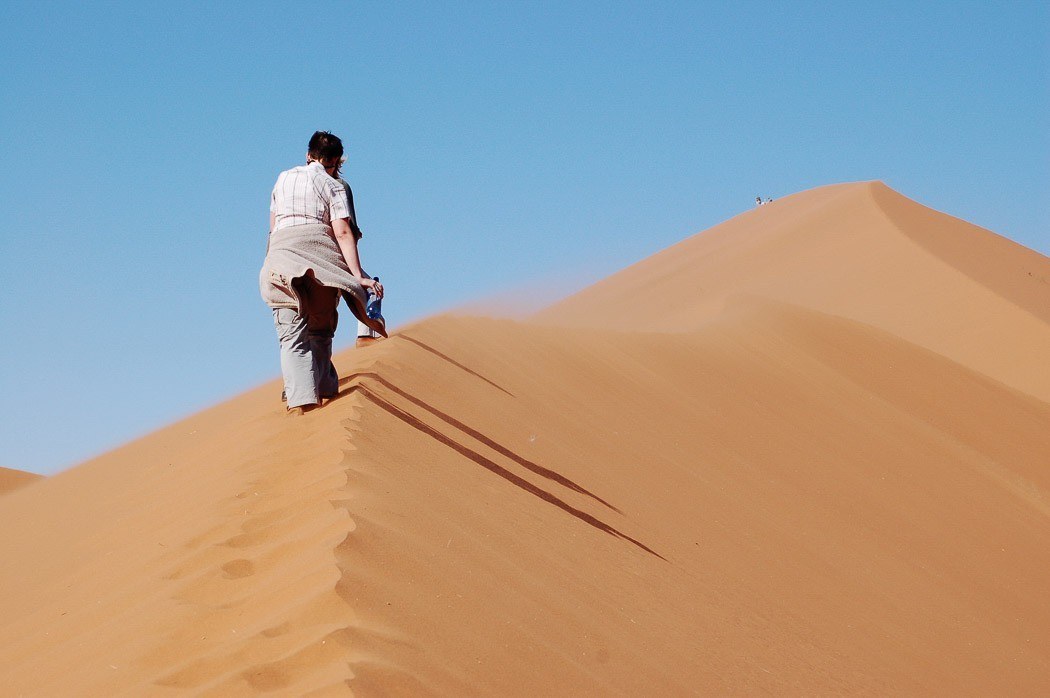 person walking up big daddy sand dune in namibia - taken from behind
