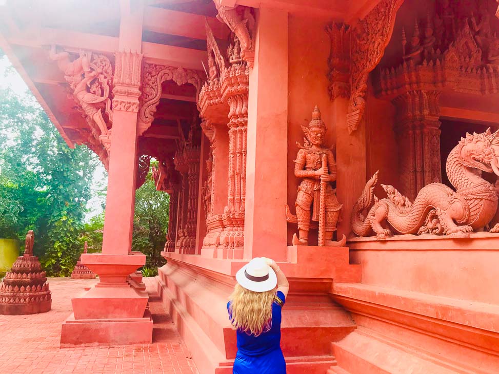 woman in hat photographing red temple