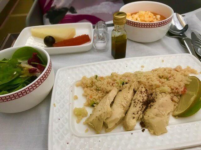 business class flight dinner of grilled chicken with salad and cheese