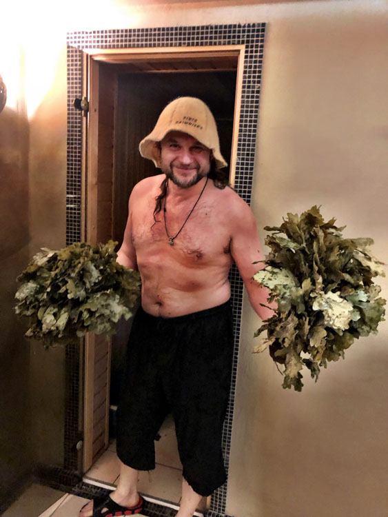 Man with birch branches for whisking outside a sauna