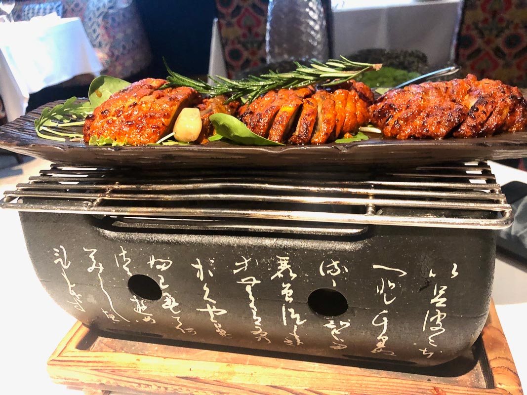 black grill with japanese writing and sliced meats on top