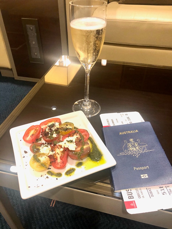 Emirates Business Class Review: Is it Worth It? 29 glass of champagne, plate with tomatoes and australian passport