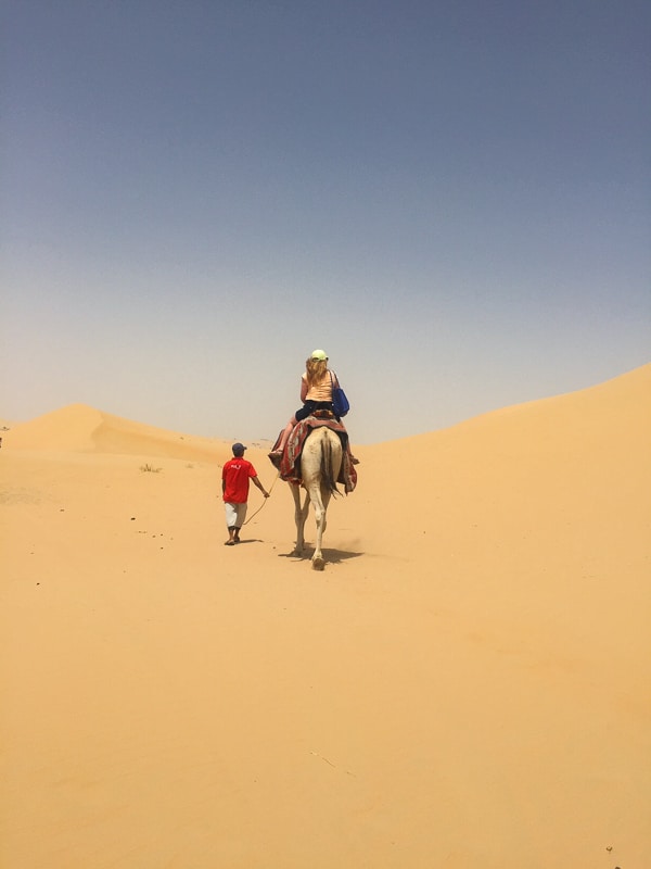 3 Day Dubai Itinerary for First Time Visitors 39 woman on camel being led by man from behind in the distance