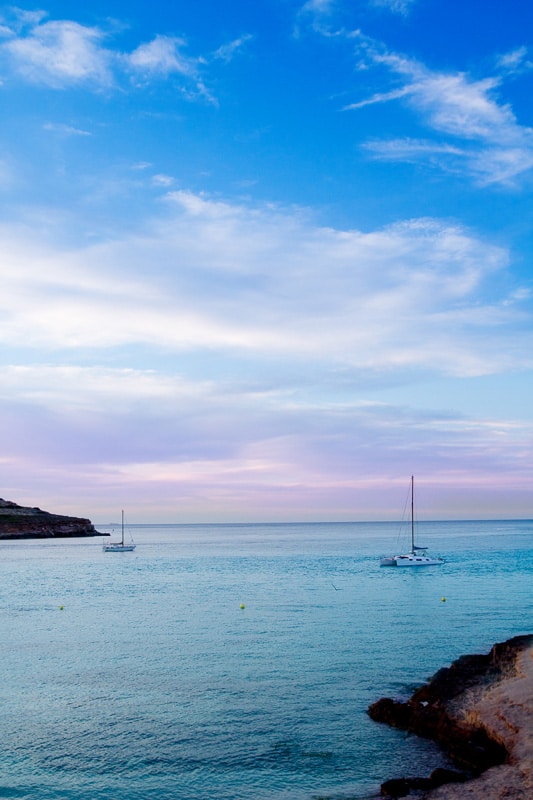 13 Spectacular Sunsets in Ibiza You Won't Want to Miss (2022) 9 cala conta beach ibiza with sailboat